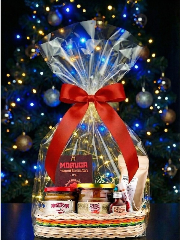 Dárkový koš nejpálivější dobroty, s celofánem, červenou stuhou před Vánočním stromem